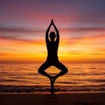 Mulher praticando yoga ao nascer do sol na praia, simbolizando paz e autocuidado