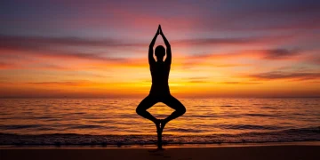 Mulher praticando yoga ao nascer do sol na praia, simbolizando paz e autocuidado