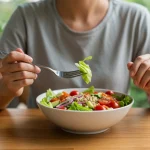 Mindful Eating: Coma Consciente e Transforme sua Relação com a Comida em 60 Dias Pessoa comendo salada colorida de forma consciente, focando na experiência alimentar.