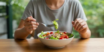 Pessoa comendo salada colorida de forma consciente, focando na experiência alimentar.