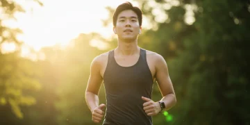 Pessoa correndo em um parque, sorrindo, exemplificando a conexão entre exercício e saúde mental.