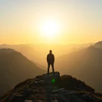Pessoa em pé no topo de uma montanha, simbolizando resiliência e superação de desafios em 2025